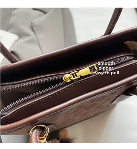 Close-up of smooth gold metal zipper on dark brown vintage leather shoulder bag