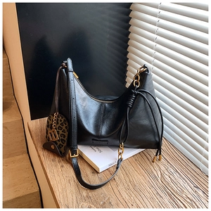 Detail of black crescent hobo bag with gold chain strap and leopard coin purse charm