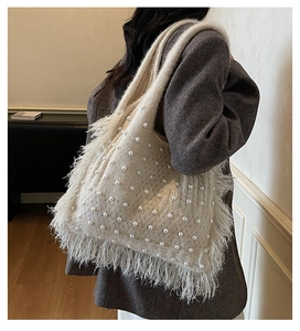Detailed close-up of cream knit shoulder bag with pearls and delicate fringe texture