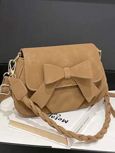 Sac bandoulière vintage caramel avec nœud et sangle tisée sur des livres