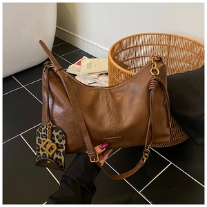 Detailed view of coffee brown leather tote with a leopard print charm and golden B-logo