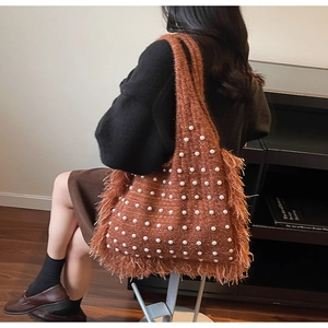 Detail view of brown knit tote bag with white pearl accents and shaggy fringe trim
