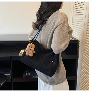 Detail einer großen schwarzen Canvas-Tragetasche mit 3D-Logo und süßem Bärenanhänger
