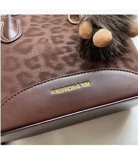 Macro detail of brown leopard print handbag with golden logo and soft texture