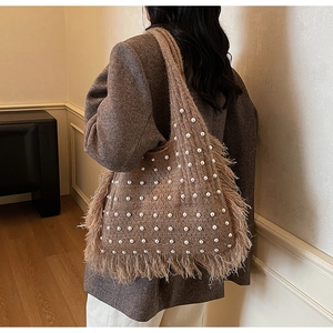 Detail of brown knit tote bag featuring white pearl accents and long bohemian tassels