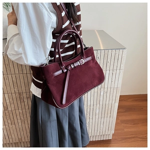 Detail of burgundy baguette bag with matte suede texture and metal buckle strap design