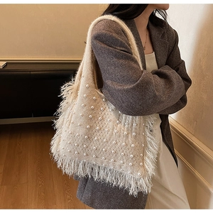 Close-up of knit tote bag with elegant pearls and soft feather fringe trim