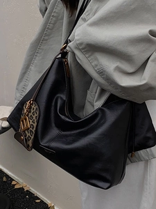 Minimalist black leather tote bag with leopard charm and gold letter B detail