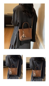 Detail of leopard print tote bag with plush monster charm and golden logo lettering
