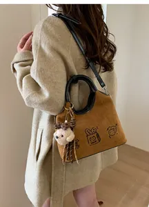 Détail d'un sac en daim marron avec imprimés de dessins animés et pendentif chien peluche