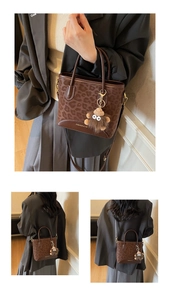Detail of leopard print tote bag featuring a cute plush monster charm and adjustable strap