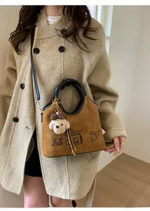 Détail du sac en daim marron avec motifs de chats mignons et pendentif ours en peluche