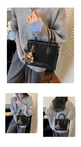 Detail of black leopard print crossbody bag with gold logo and plush charm accessory