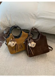 Détail des sacs cabas en daim avec broderie de gâteaux et porte-clés en peluche