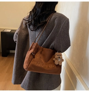 Braune Wildleder-Einkaufstasche mit Logo-Prägung und süßem Teddybär-Anhänger Detail