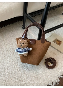 Brown frosted suede bucket bag detail with contrast leather handle and teddy bear charm