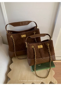 Close-up of brown bucket bag with quilted stitching, chain strap and gold twist lock