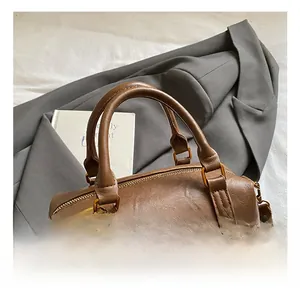 Detailed close-up of brown vintage leather Boston bag with plush ball and tassel charm