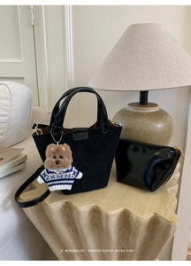 Detail view of black frosted suede bucket bag with inner pouch and plush dog charm