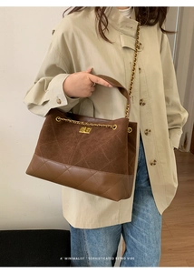 Detail of dark brown quilted suede bucket bag with gold chain and metal twist lock