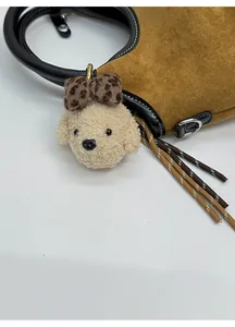 Détail d'un pendentif chien en peluche avec nœud léopard sur un sac à main en daim