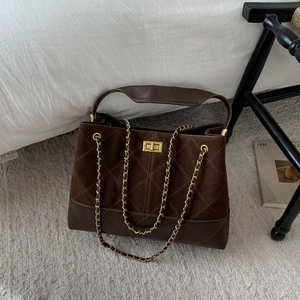 Close-up of brown quilted suede bucket bag with gold chain strap and square metal lock