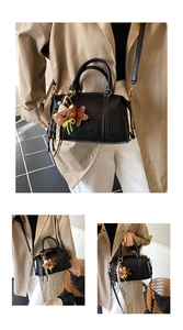 Detail of black Boston handbag with brand engraving and cute brown bear plush charm