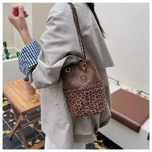 Detail of a leopard print bucket bag with gold chain strap and quilted leather texture