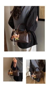 Detail of dark brown leather Boston bag with embossed letters and cute bear pendant charm