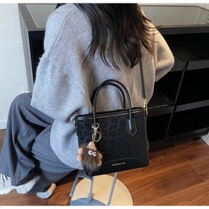 Detail of black leopard print crossbody bag with plush charm on a fashion model