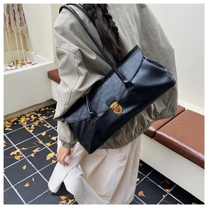 Detail of a vintage black square leather bag with a gold metal clasp and Ginkgo leaf background