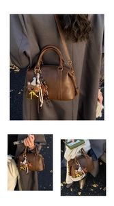 Detail of vintage brown Boston bag featuring teddy bear charms and striped ribbon decor