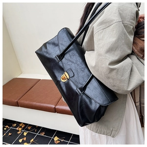 Side view of woman carrying black vintage textured leather shoulder bag with gold lock