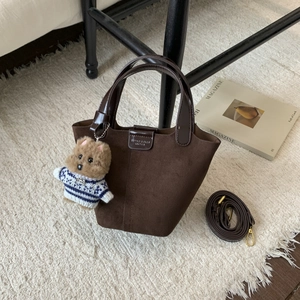 Detail view of dark coffee suede bucket bag with leather handle and cute bear charm