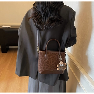 Detail of leopard print tote bag with plush charm and adjustable shoulder strap
