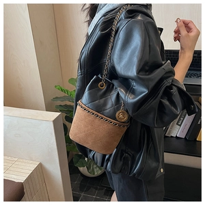 Detail of suede and quilted leather bucket bag with gold chain and logo charm