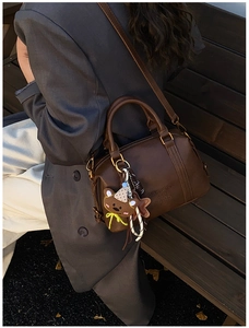 Detail of a brown Boston bag featuring ZSKERT PARIS embossing and a plush bear charm