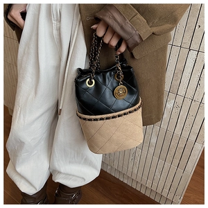 Close-up of quilted bucket bag featuring black leather, beige fabric and gold chain
