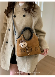 Détail du sac vintage en daim marron avec imprimé cake et charm de chien en peluche
