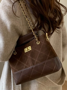 Brown quilted bucket bag with chain strap and gold twist lock shown on model's shoulder