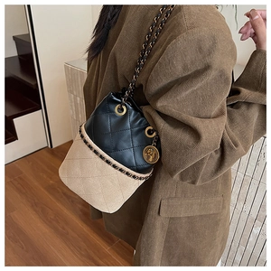 Detail of a leopard bucket bag featuring black quilted leather and beige suede with a gold chain