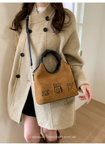 Détail d'un sac bandoulière rétro en daim avec motifs de dessins animés et anses noires