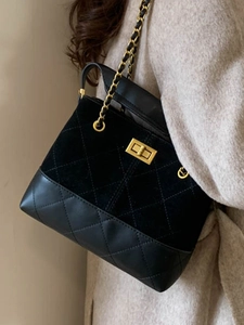 Chic black quilted bucket bag with gold chain strap shown on model in beige coat