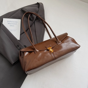 Detail of vintage brown rectangular shoulder bag with golden metallic clasp on grey blazer