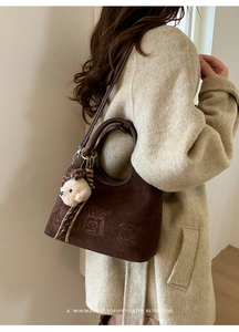 Détail du sac bandoulière vintage en daim marron avec broderie chat et gâteau mignonne