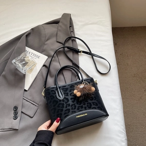 Detail of black leopard print crossbody bag with gold text and plush bear charm