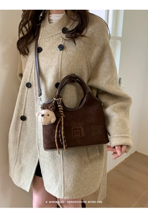 Détail du sac bandoulière en daim marron avec broderie cartoon et breloque ourson