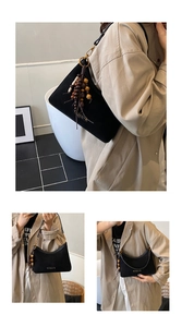 Detail of black leather crescent bag with wooden bead tassel and gold metal buckle