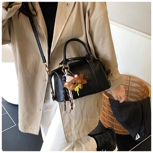 Detail of black leather Boston bag featuring AIR PARIS embossing and cute bear charm