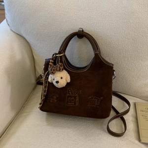 Détail du sac en daim marron avec broderie cake et breloque chien en peluche